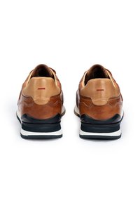 Baskets en cuir marron avec une finition texturée, de forme arrondie et semelle noire contrastante ; présentent un accent rouge minimal au niveau du talon.