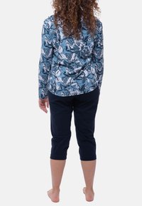 Sininen ja valkoinen kukkakuviollinen, pitkähihaisuus paita; yhdistetty tummansinisiin, lihavoidun lahkeen housuihin. Pehmeä kangas ja rento istuvuus.