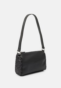 Černá ramenní taška s hladkým předním dílem, bočními panely pokrytými flitry a jedním širokým popruhem, umístěná na čistém bíl�ém pozadí.