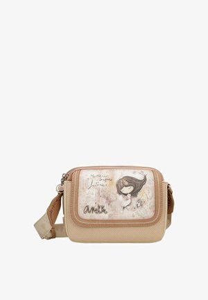 Bolso bandolera beige con un acabado texturizado, que presenta un panel frontal transparente con una niña de dibujo animado y texto. Correa ajustable y cierre de cremallera.