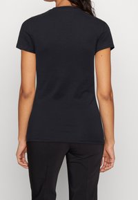 Camiseta de algodón negra con un diseño ajustado, mangas cortas y cuello redondo. Textura suave y sin patrones ni elementos visibles.