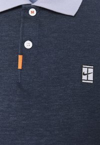 Námořnická modrá polo košile s texturovanou tkaninou, s knoflíkovým zapínáním a světle šedým límcem. Obsahuje oranžový akcent a vyšívané logo.