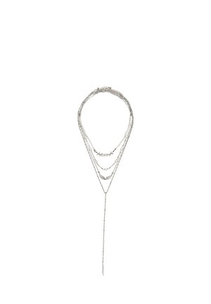 Collana argentata a più strati con più catene sottili, piccoli ciondoli decorativi e una lunga catena pendente al centro in basso.