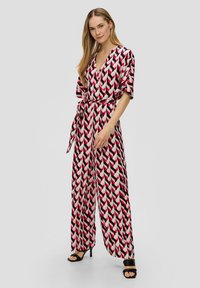 Rood, zwart en witte jumpsuit met een diep V-hals, korte mouwen, een strik taille en wijde pijpen. Soepele stoftextuur.