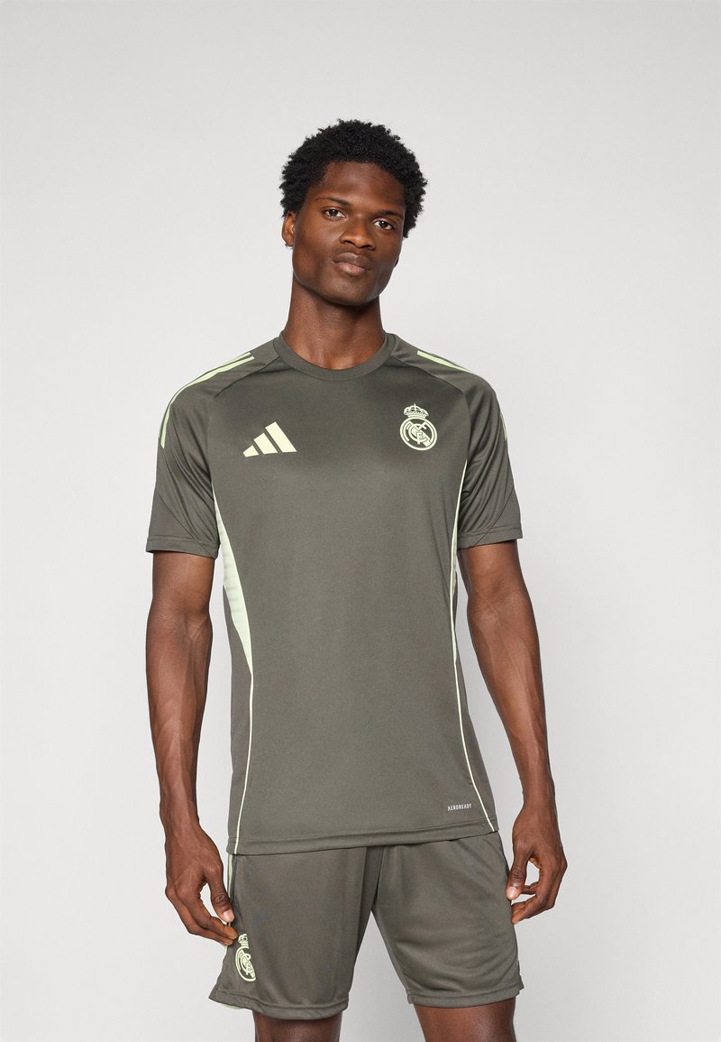 Jersey atlético gris con detalles en verde claro, que presenta el logo del Real Madrid. Diseño de manga corta y cuello redondo, hecho de una tela ligera.