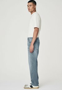Jeans gri deschis, cu o croială dreaptă și un design clasic cu cinci buzunare, asortați cu un tricou alb simplu, cu mânecă scurtă, și adidași.