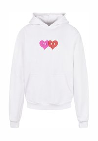 Vit hoodie med en framficka, försedd med två tecknade hjärtdesigner i rosa och rött med ögon, leende uttryck och mjuk textur.