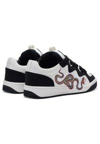 Black and white sneakers featuring a snake design. Material is smooth leather with a textured black sole and black laces.