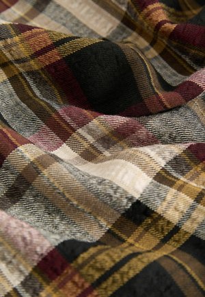 Tissu tissé avec un motif à carreaux dans des teintes de bordeaux, noir, jaune et beige. Surface texturée avec des plis doux et irréguliers et une épaisseur de fil variable.