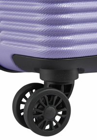 Valigia rigida viola con strisce diagonali testurizzate. Presenta una base nera e ruote resistenti con un design a razze per la mobilità.
