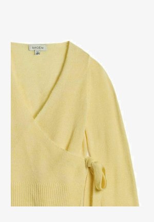 Pehme kollane mähissärkk pikkade varrukatega, soonikkoes äärega ja külgsidega lõpetusega, millel on V-kaelus ja kaeluse sees brändi silt.