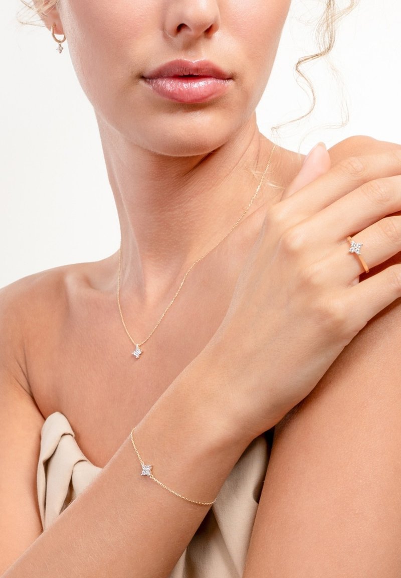 Goldfarbene Schmuckset mit einer sternförmigen Anhänger-Halskette, einem Stern-Armband und einem Sternring, die alle mit funkelnden Akzenten verziert sind.