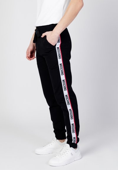 Czarne dresy z kontrastowymi białymi i czerwonymi paskami po bokach, z napisem "Moschino". Zaprojektowane z kieszeniami i elastycznym pasem ze sznurkiem.