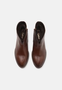 Paire de bottines en cuir marron avec fermetures éclair latérales, bouts arrondis et semelles intérieures de marque visibles, vues de dessus sur un fond blanc.