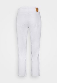 Pantalones vaqueros de algodón blanco con un diseño de pierna recta, que presentan un dobladillo desflecado, dos bolsillos traseros y una etiqueta de marca de cuero marrón en la cintura.