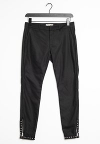 Svarta åtsittande byxor med framfickor, med dragkedjor och nitar vid ankeln. Tillverkade av ett glatt tyg med en elegant design.