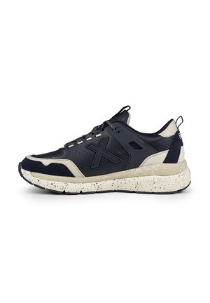 Scarpa sportiva blu marino e beige con tomaia testurizzata, suola intermedia maculata e tallone rinforzato. Dotata di sistema di allacciatura e dettaglio del logo laterale.