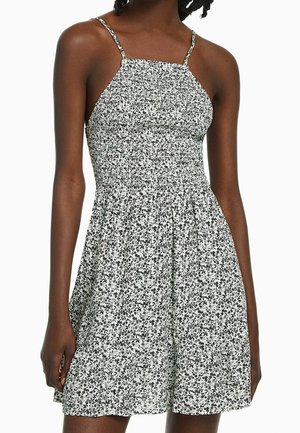 Schwarz-weißer Blumenkleid mit tailliertem Oberteil, dünnen Trägern und einem ausgestellten Rock, gefertigt aus einem leichten Stoff mit TEXTURIERTEM Muster.