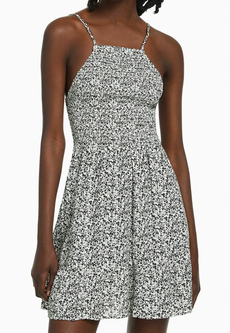 Black and white floral dress with a fitted bodice, thin straps, and a flared skirt, made of lightweight fabric with a textured pattern.