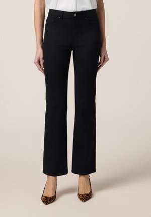 Zwarte flared jeans van denim met een gladde textuur. Voorzien van een knoop aan de voorkant, riemlussen en zijzakken. Draagt met gemusterde hakken.