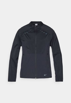 Nike jacket in black fabric with a high collar, full zip, and blue detailing along the shoulders. Features zippered side pockets.