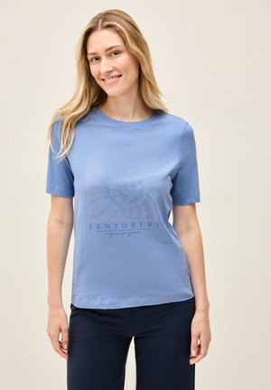 T-shirt à manches courtes bleu clair en coton doux, avec un imprimé décoratif portant le texte "Santorin" et un motif de soleil en strass.