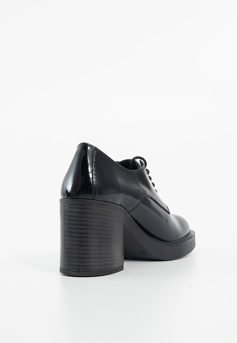 Chaussures à talons en cuir verni noir avec un bout arrondi, dotées d'un talon épais à nervures et d'un design lacé. Texture lisse et détails minimaux.