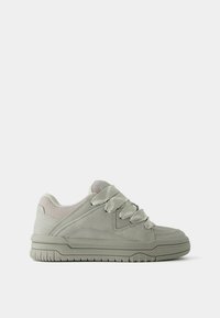 Jasnoszare sneakersy z zamszową i siateczkową cholewką, wyściełanym kołnierzem, szerokimi sznurowadłami i teksturowaną gumową podeszwą. Gładkie kontury i minimalistyczne akcenty wzornicze.