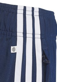 Námornícke športové šortky s bielymi bočnými pruhmi, so zipsovým vreckom a malou nášivkou s dizajnom globusu. Textúrovaná tkanina.