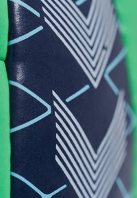 Grön vadderad kant omger en marinblå yta med strukturerade zigzagmönster i ljusblått. Designen har en geometrisk stil.