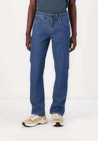 Blue denim jeans with a straight fit. Features include five pockets, a button closure, and stitching accents along the seams.