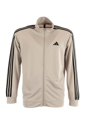 Veste zippée beige clair en tissu lisse avec des accents noirs à trois bandes sur les manches et un petit logo noir sur la poitrine.
