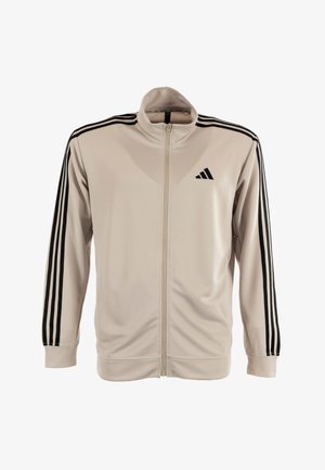 Veste zippée beige clair en tissu lisse avec des accents noirs à trois bandes sur les manches et un petit logo noir sur la poitrine.