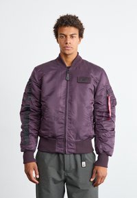 Paarse bomberjack gemaakt van glanzend nylon, met een ribbelkraag en -manchetten, ritsluiting, zijzakken en een logopatch op de borst.