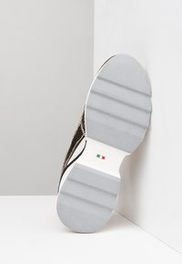 Sneaker con suola in gomma bianca e grigia, caratterizzata da una parte superiore in rete nera tessurizzata e sottili accenti metallici. Prodotta in Italia, misura 37.