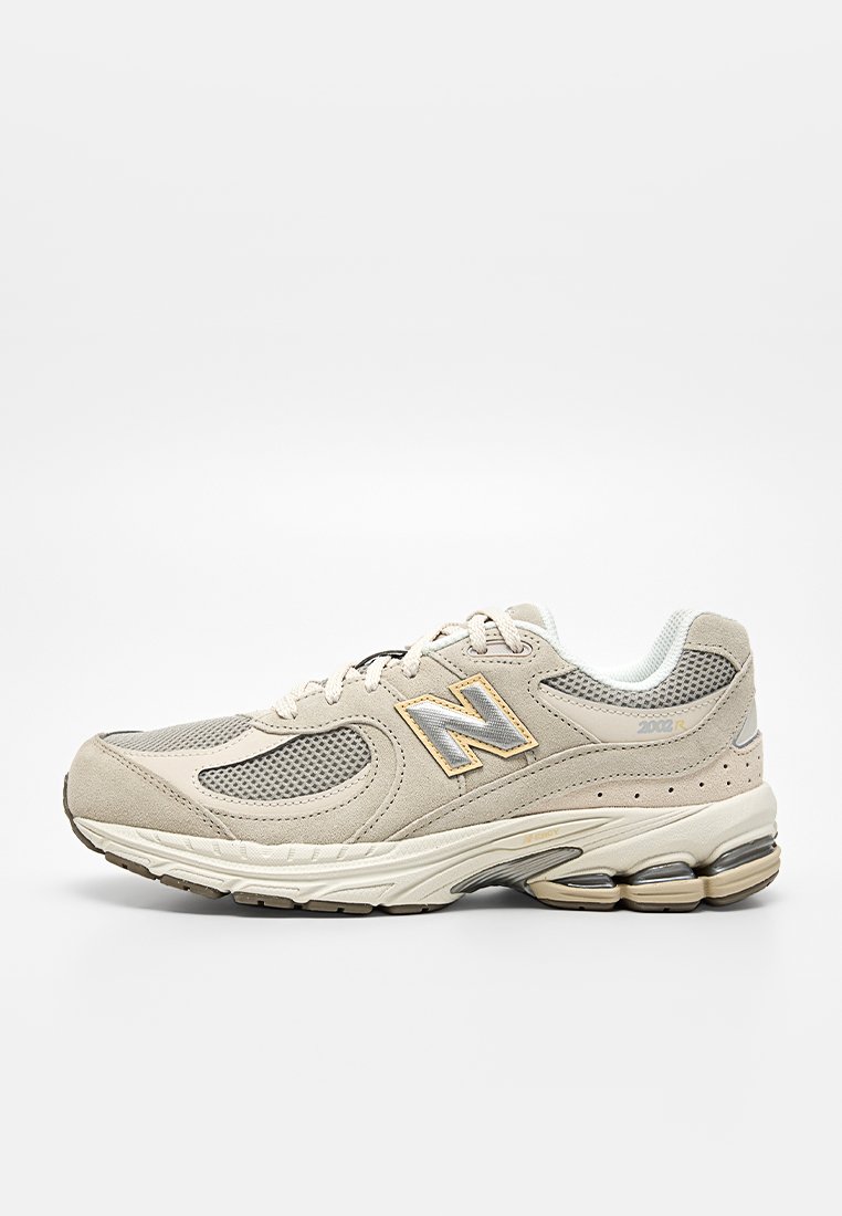 Sneaker Beige New Balance 2002R con pannelli in mesh, sovrapposizioni in suede e suola ammortizzata con air pod visibili, mostrata dal lato esterno.