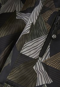 Bunt gemusterter Stoff mit geometrischen Motiven in Grün, Braun und Creme, mit einer strukturierten Oberfläche. Enthält ein schwarzes Reißverschlussdetail.