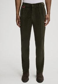 Pantalons en velours côtelé vert avec une fermeture à bouton et des poches latérales. Présente une anse rouge sur la taille. Texture lisse et coupe droite.
