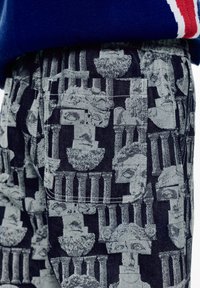 Traperice sivo grafičkim uzorkom klasičnih skulptura i stupova, s strukturiranim krojem i detaljem na zakrpa džepu.