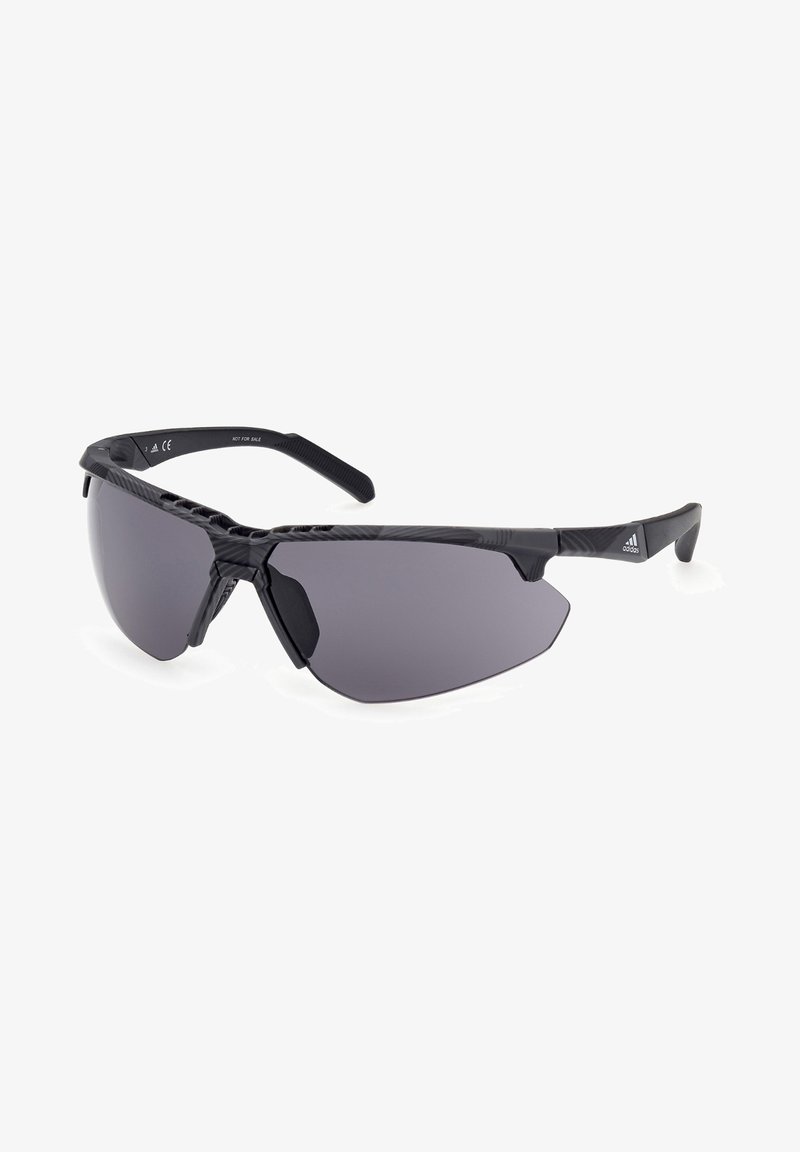 Lunettes de sport noires avec un design large et enveloppant, verres teintés gris et accents en caoutchouc texturé sur les tempes pour une meilleure prise.