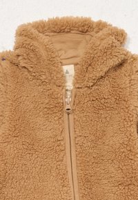 Chaqueta de bebé suave y marrón, con capucha y cremallera central, diseñada para brindar calidez y comodidad.