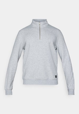 Svetlo sivý mikina s polovičným zipsom, dlhými rukávmi, rebrovanými manžetami a spodným lemom, a malou logom štítkom blízko dolného ľavého rohu. Mäkkučká textúra.