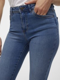 Høyt liv blue denim bukser med en glatt tekstur, med kontraststing, frontlommer og detaljer med bronsefarge på knappen.