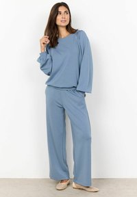 Conjunto de loungewear de dos piezas en azul claro que presenta una parte superior relajada con mangas abullonadas y pantalones de pierna ancha, confeccionado en una tela suave con una textura lisa.