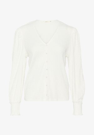 Valge pika varrukaga pluus V-kaelusega, tekstuurse kangaga, nööbitava esiosa ja kogutud mansettidega. Ilma eristuvate mustrite või aktsentideta.