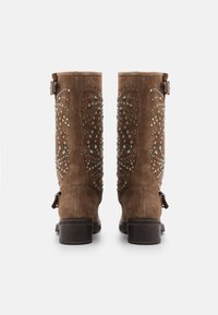 Botines de ante marrón con tachuelas decorativas y detalles en turquesa, con tacón bajo y hebilla en el lateral.