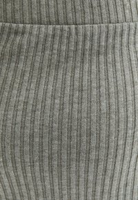 Tissu gris côtelé présentant des rayures verticales alternant textures et surfaces lisses, avec une texture douce et tricotée et un léger éclat.