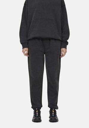 Completo bicolore grigio scuro composto da felpa a girocollo con tasca frontale e pantaloni della tuta abbinati. Tessuto texturizzato, vestibilità comoda. Sneakers nere.