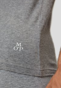 Grijze t-shirt van zacht materiaal, met een witte "M OP" logo aan de linkerkant, met platte naden en een klassiek pasontwerp.