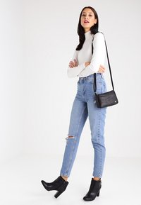Vit ribbad polotröja, ljusblå slitna skinny jeans, svarta klackade ankelboots och en liten svart axelväska.